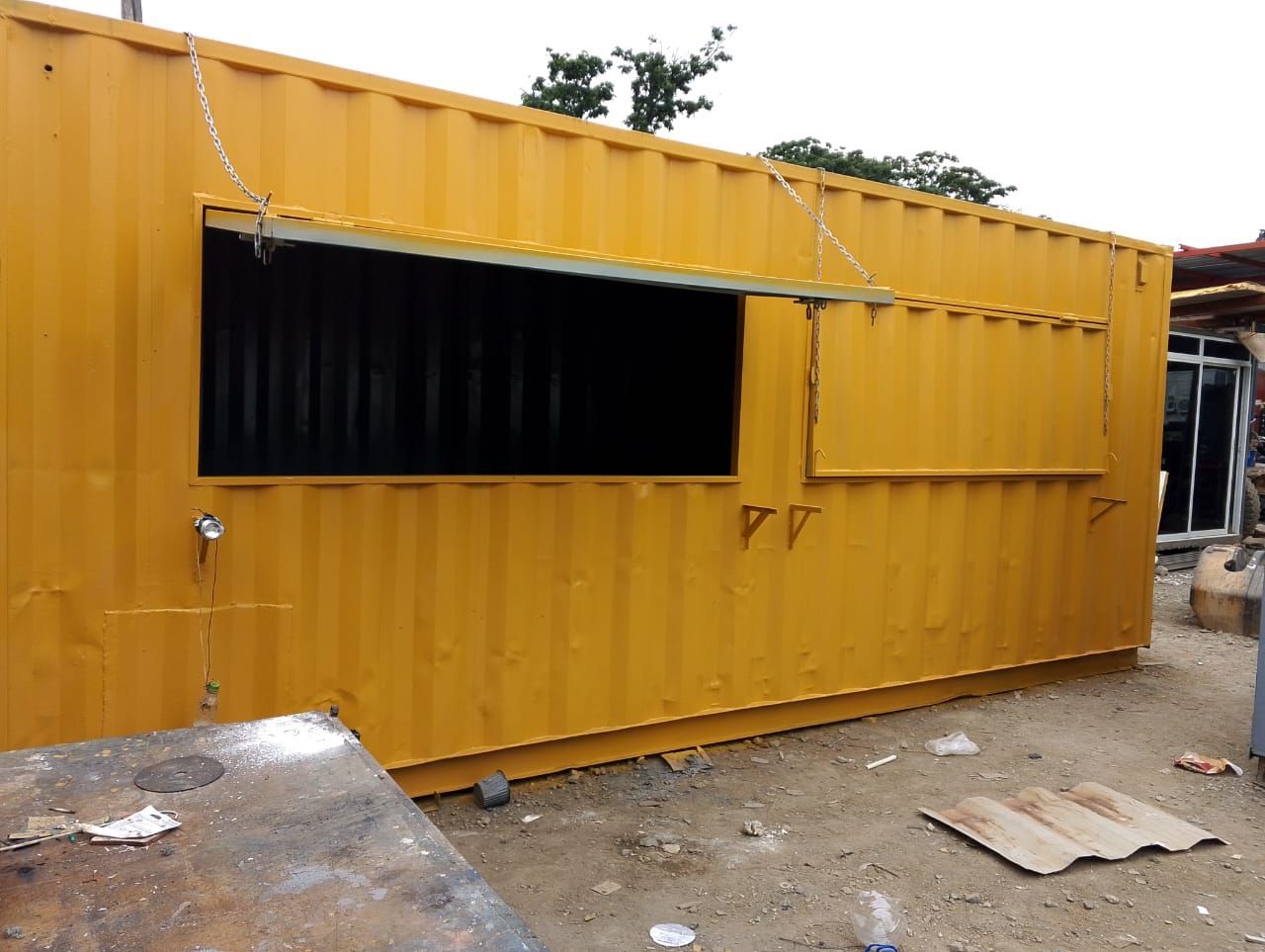 Un contenedor de transporte amarillo modificado con una gran ventana de servicio abierta,