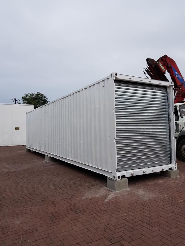 Un contenedor de almacenamiento blanco con una puerta enrollable plateada descansa sobre bloques de hormigón
