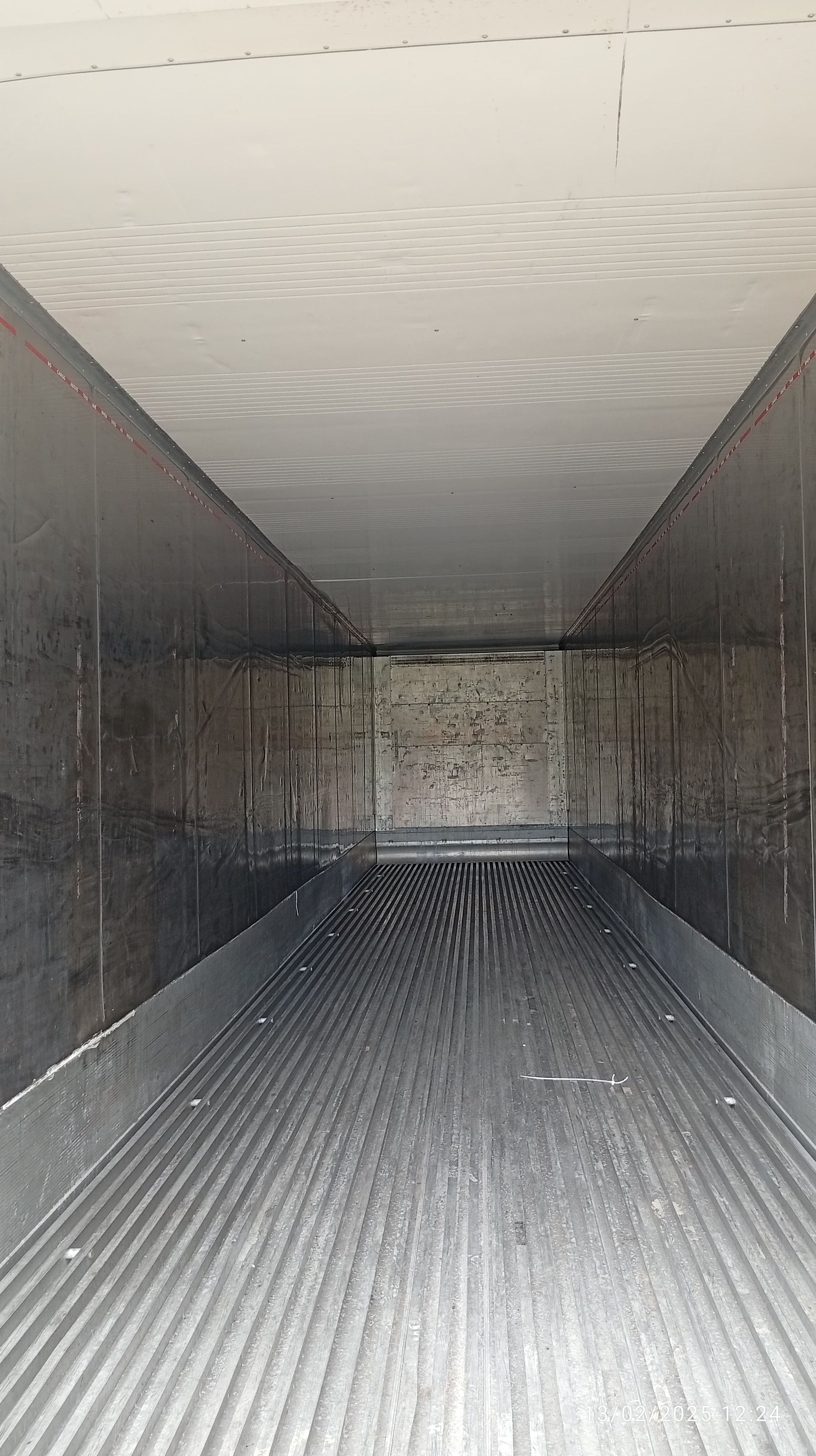 Vista interior de un contenedor de transporte vacío con suelo de metal acanalado y paredes lisas