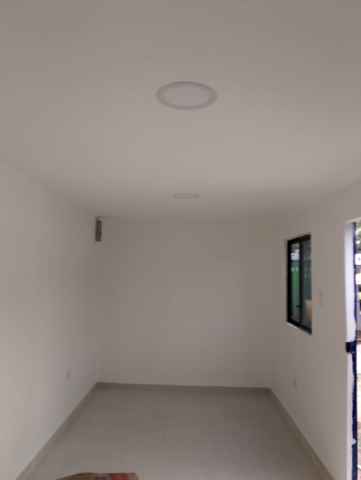 Vista del interior de una habitación minimalista con paredes blancas, suelo de color claro