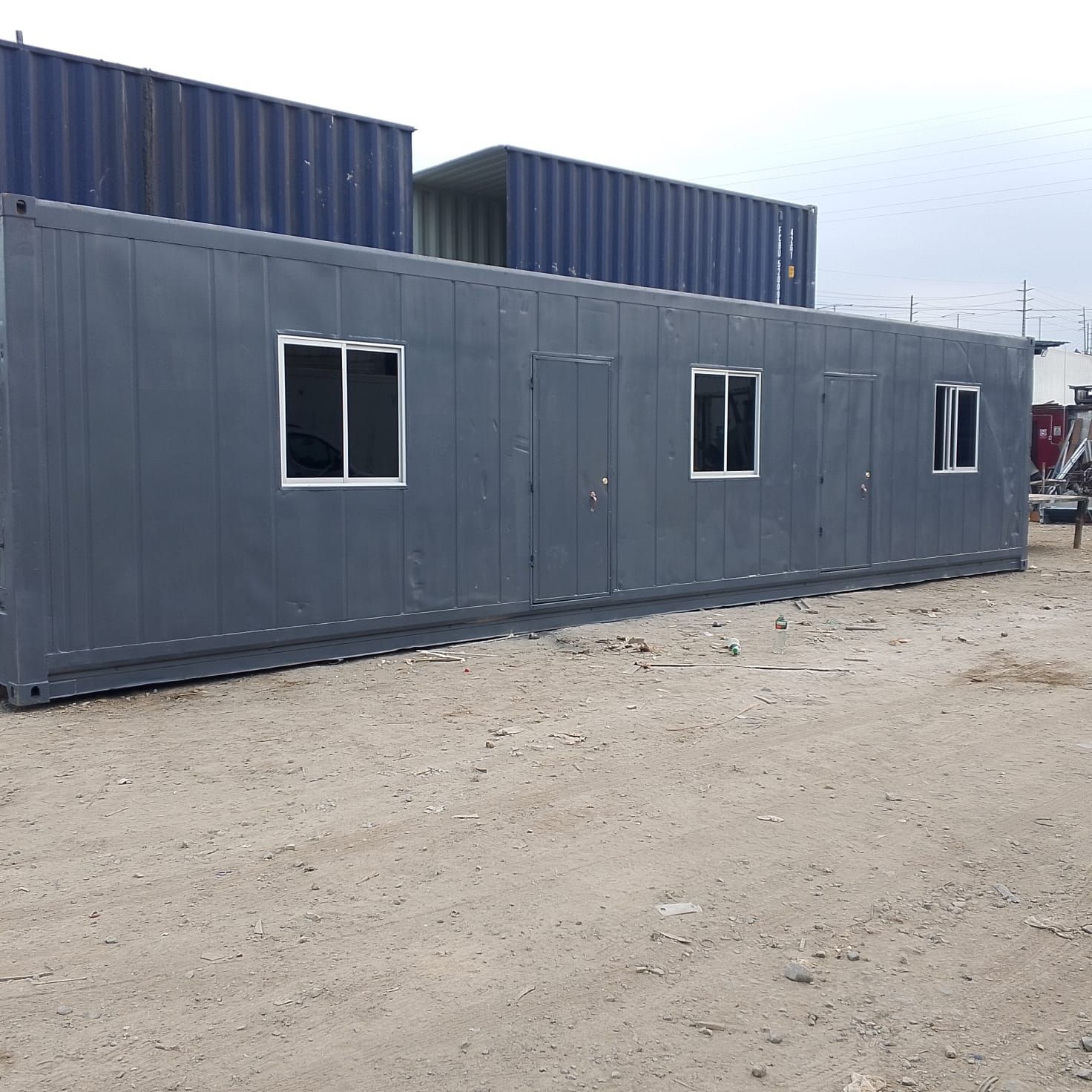Un contenedor de oficina portátil, rectangular y de color gris, con dos puertas y tres ventanas