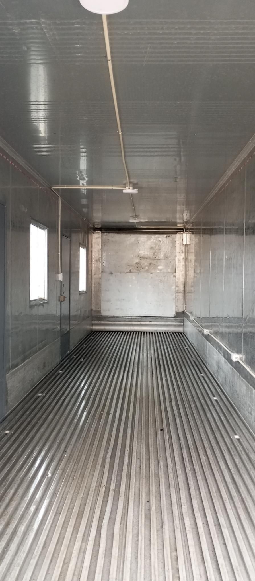 Interior de un contenedor de transporte refrigerado vacío con paredes metálicas y suelo de chapa ondulada.