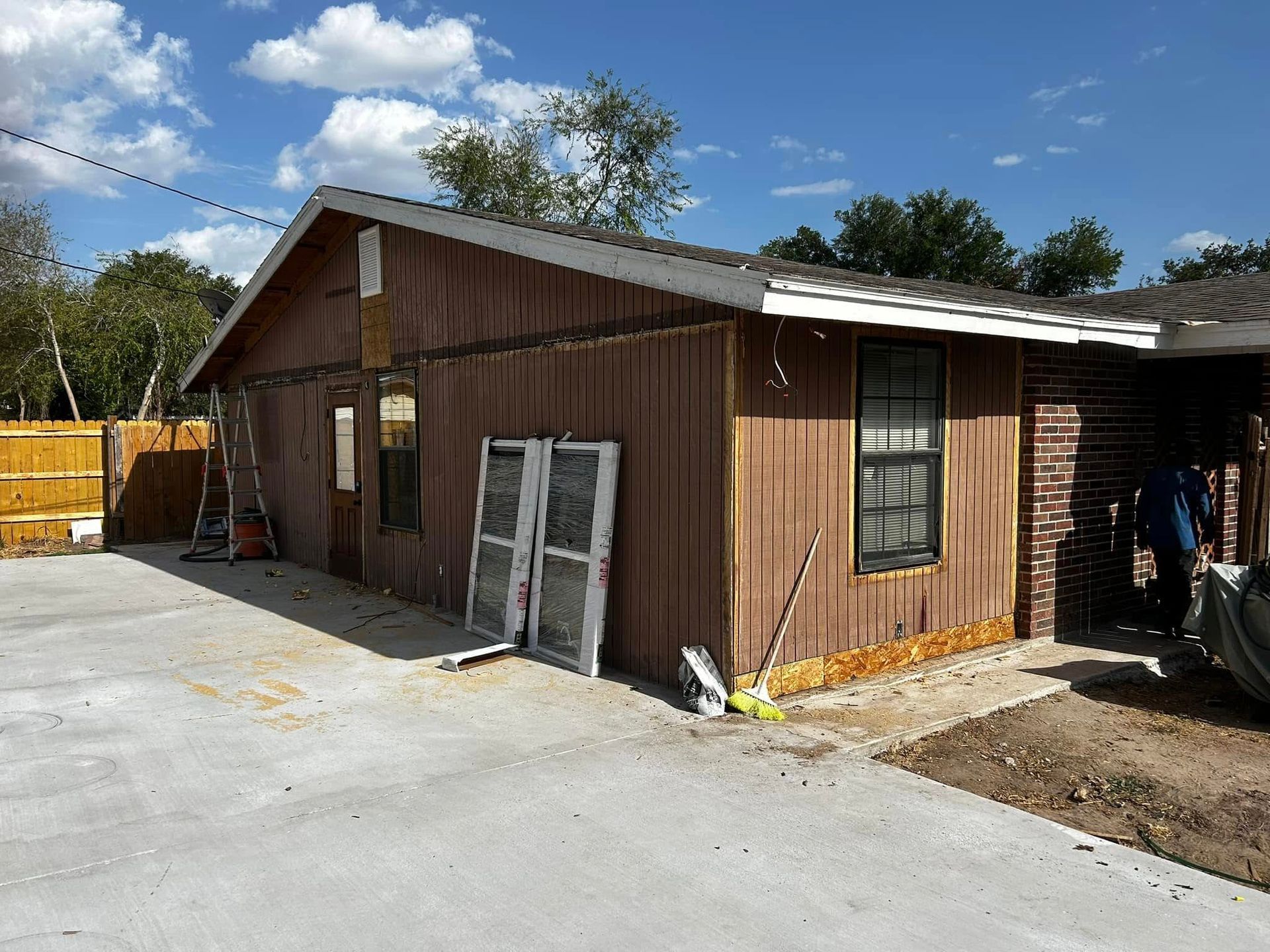 Brown wooden building with white trim beside a concrete lot under a blue sky