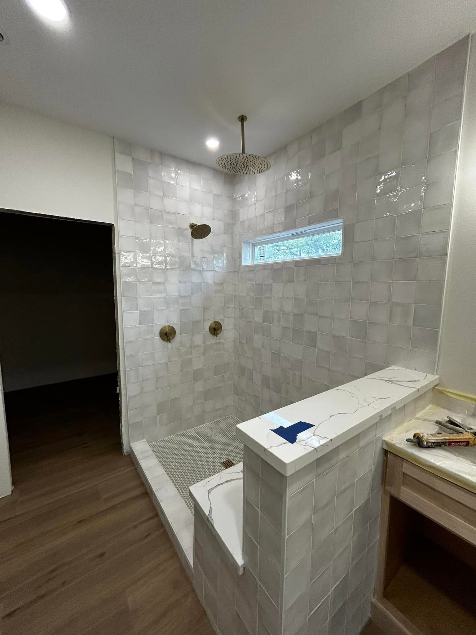 Modern tiled bathroom with walk-in shower, white vanity, and dark wood floor.