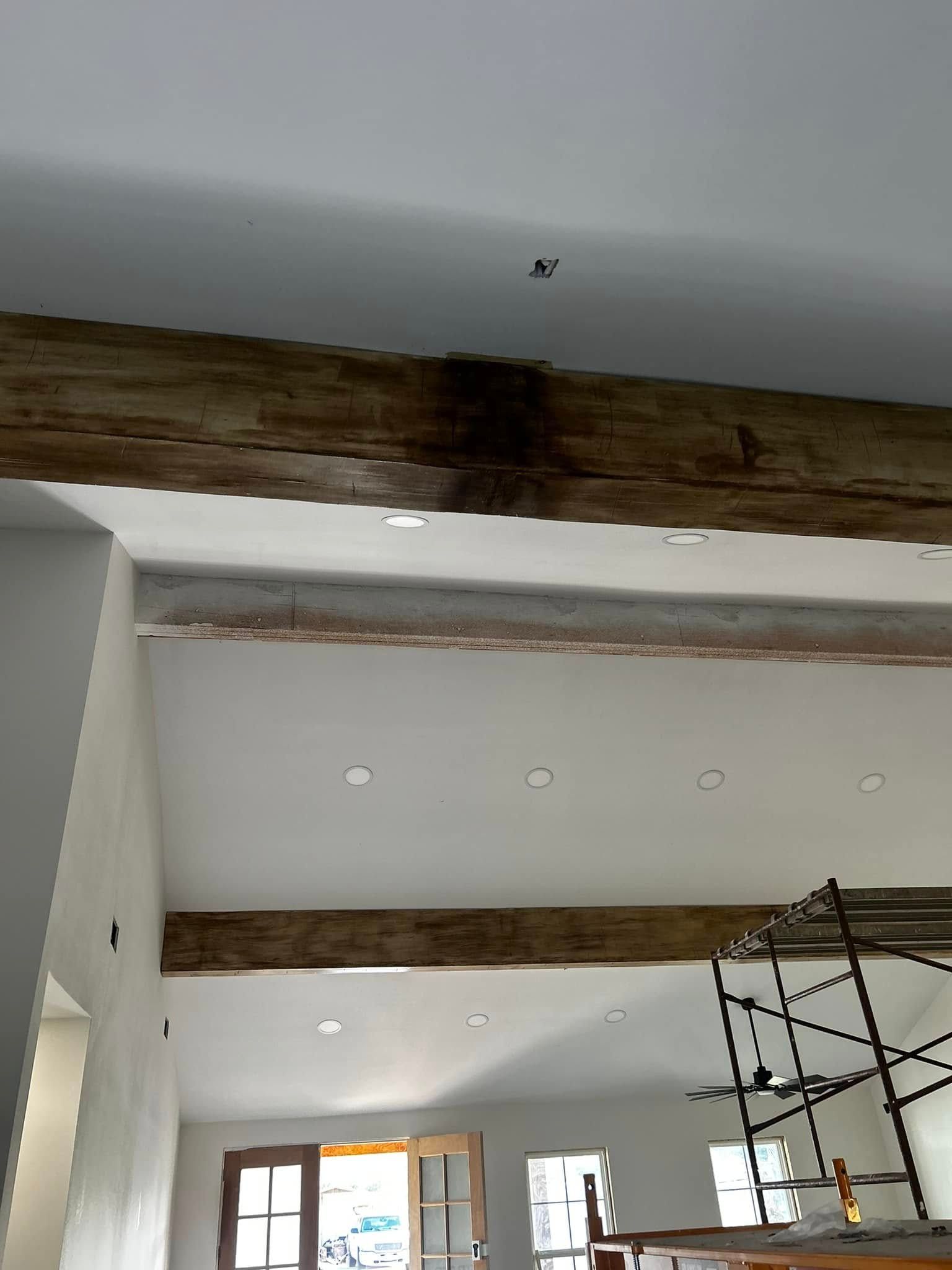 Interior room under renovation with exposed wooden beams and scaffolding near windows