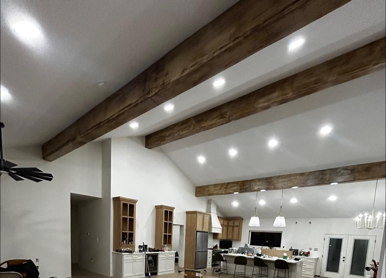 Spacious modern hall with white walls, exposed wood beams, recessed lights, and open kitchen seating area