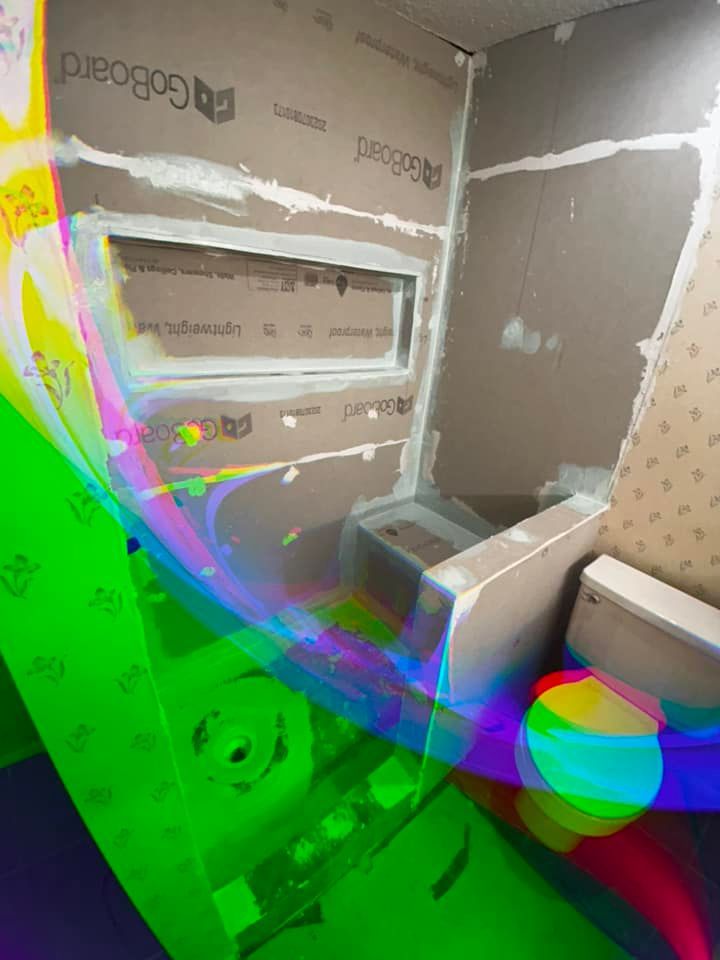 Partially tiled bathroom under renovation with a built-in tub and open wall cavities