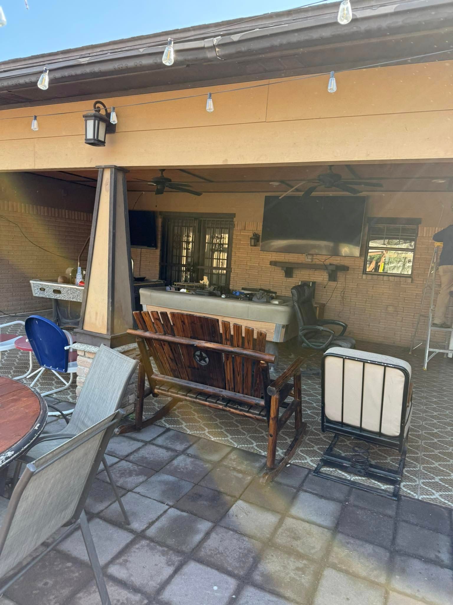 Covered patio with tiled floor, bar stools, and an outdoor kitchen sink and grill area