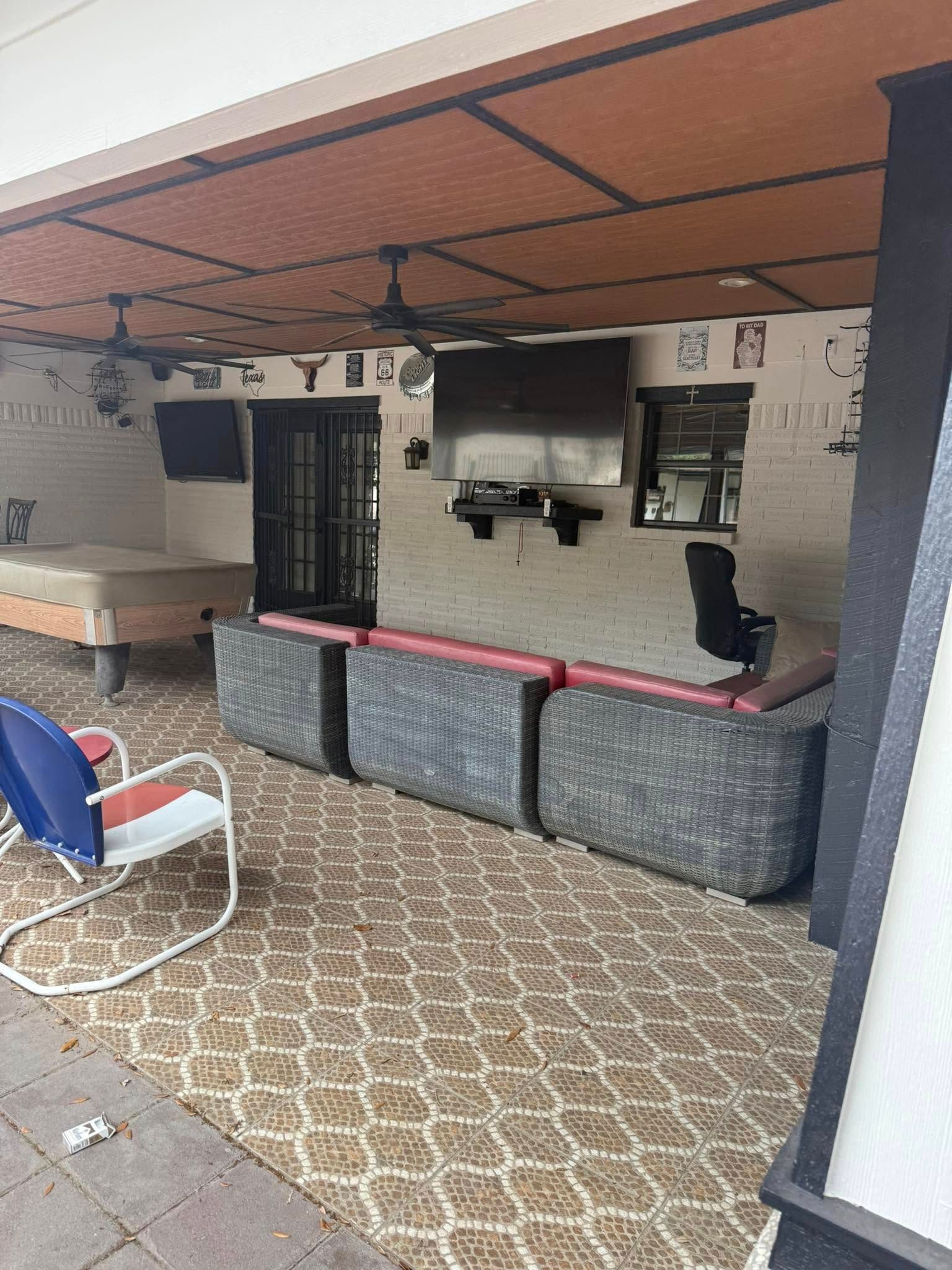 Outdoor patio bar with red countertop, stools, and patterned tile floor under a covered roof.