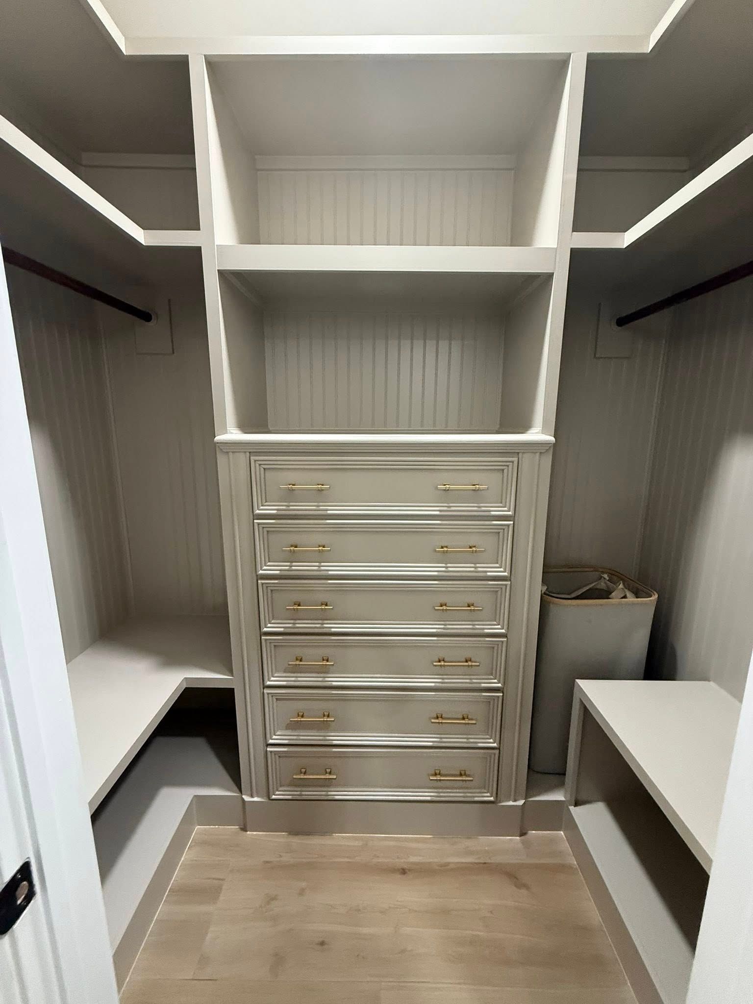 Walk-in closet with shelves, drawers, and benches in a neutral beige finish