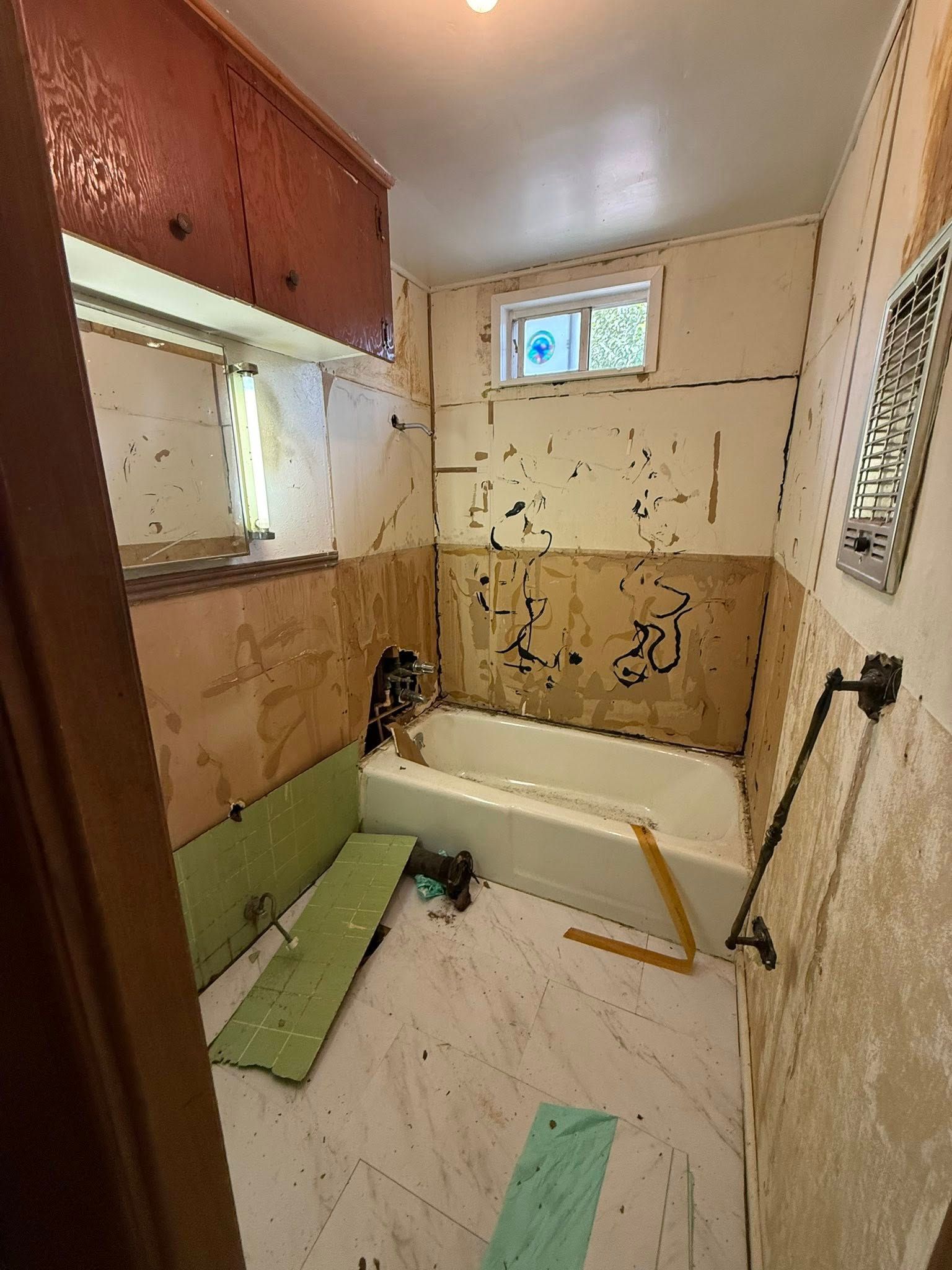 Small bathroom under renovation with a bathtub, vanity, and tools on the floor.