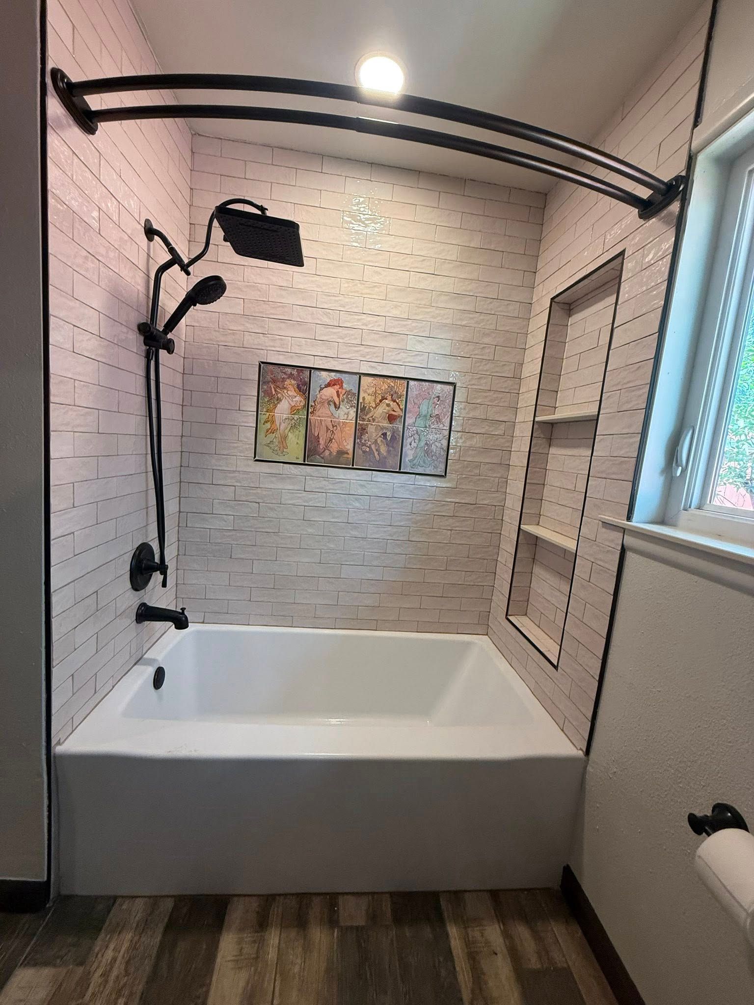 Modern bathroom with a built-in tub, black shower fixtures, white tile, and a window