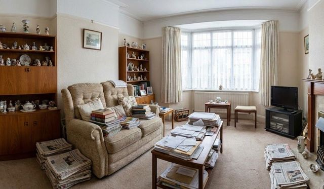 Lounge cluttered with books, ornaments and magazines before a bereavement clearance in Cardiff