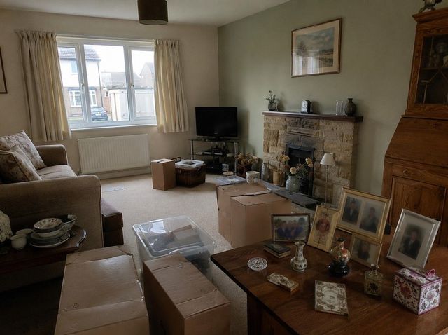 Room stacked with boxes beside a shelf of framed photos