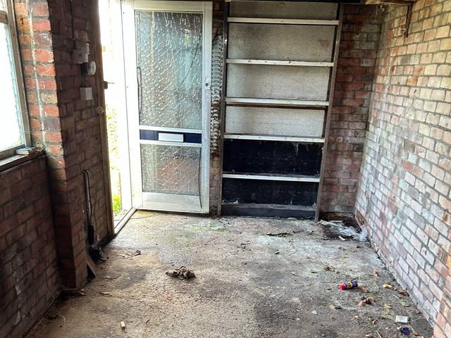 The garage emptied back to the concrete floor, with only the fixed shelving left on the end wall