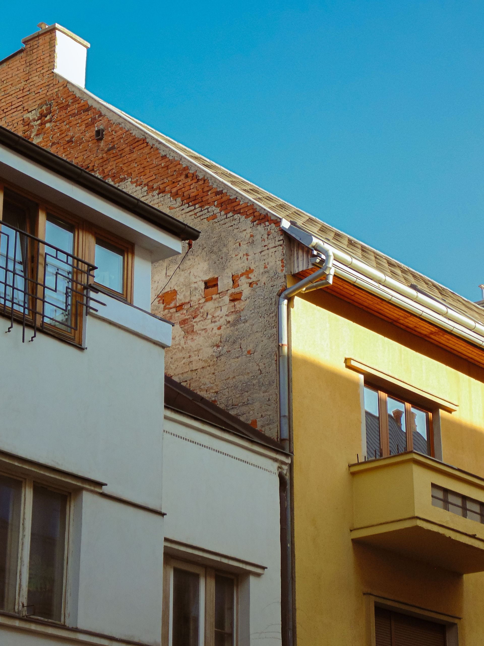 Sunlit row of colorful apartment buildings with balconies under a clear blue sky