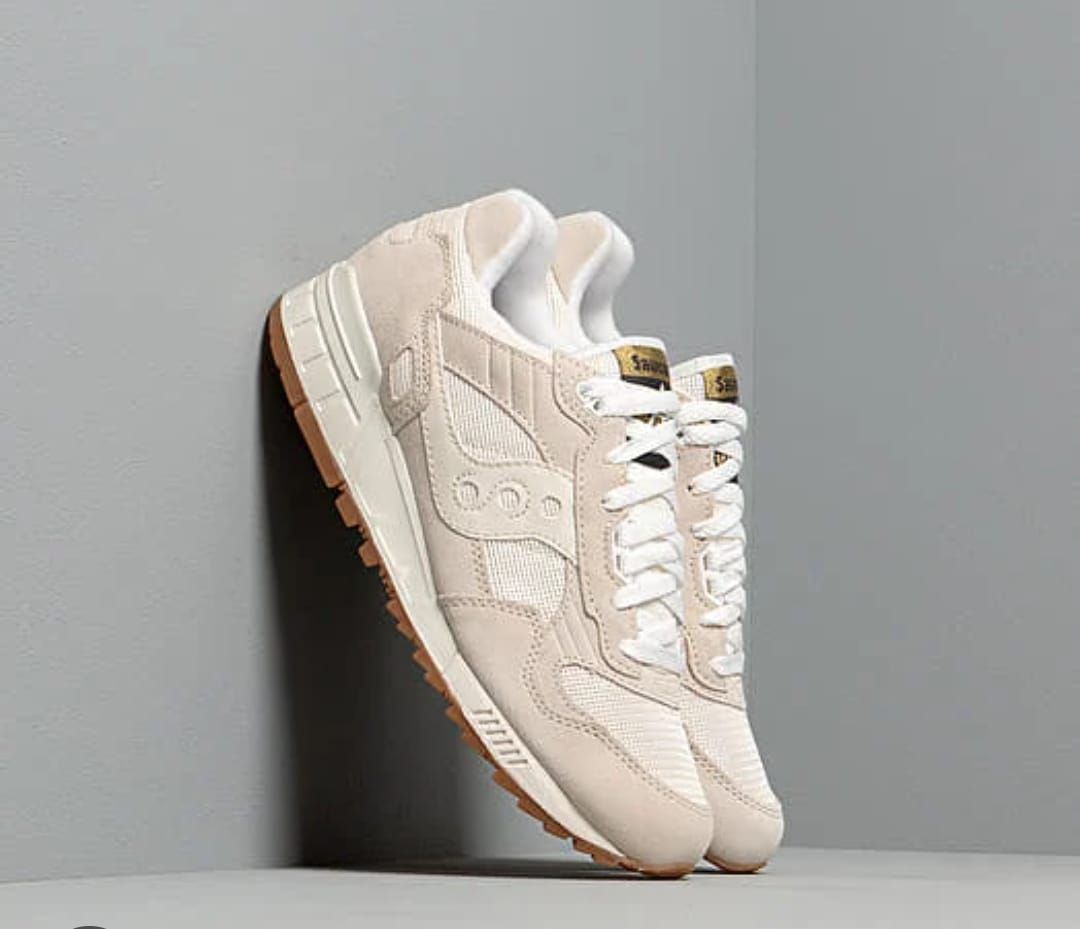 Un paio di scarpe da ginnastica bianche sono appoggiate su un tavolo bianco.