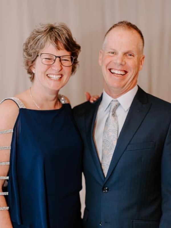 A man in a suit and tie is standing next to a woman in a blue dress.