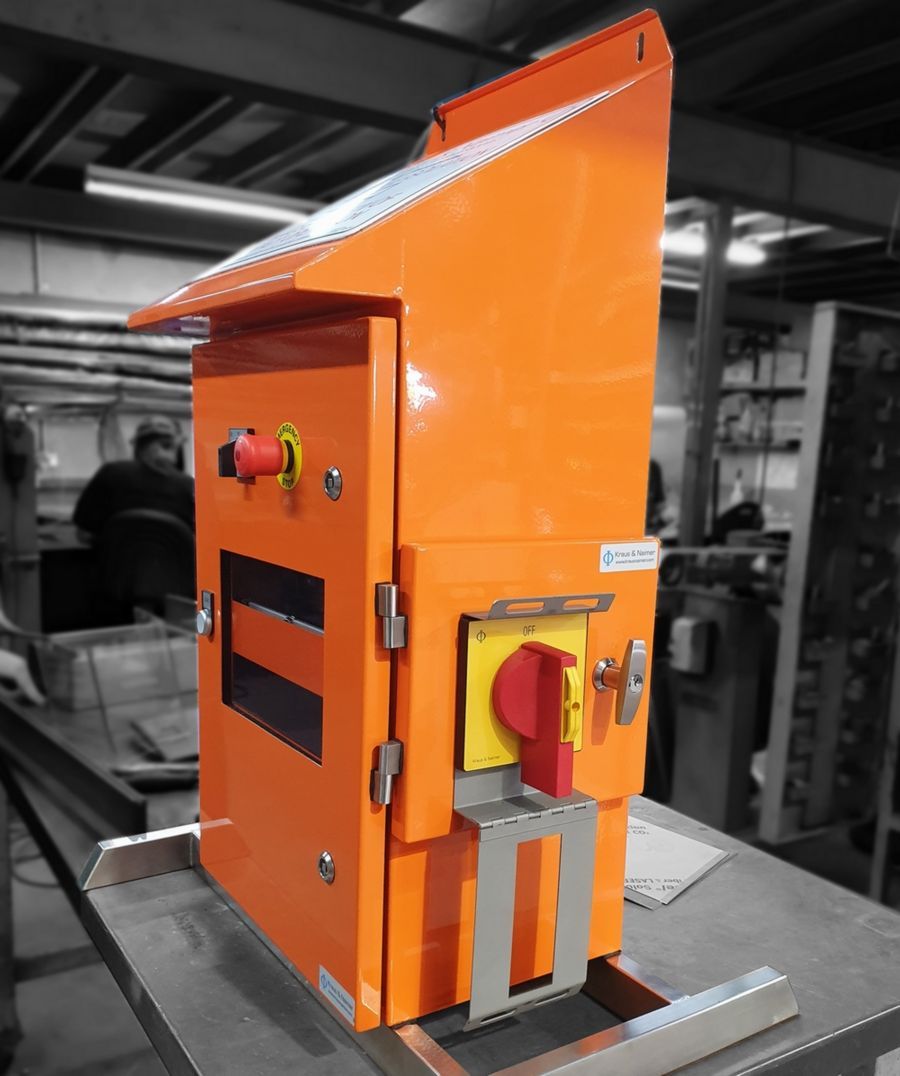 Orange electrical cabinet with a red and yellow switch and an emergency stop button.