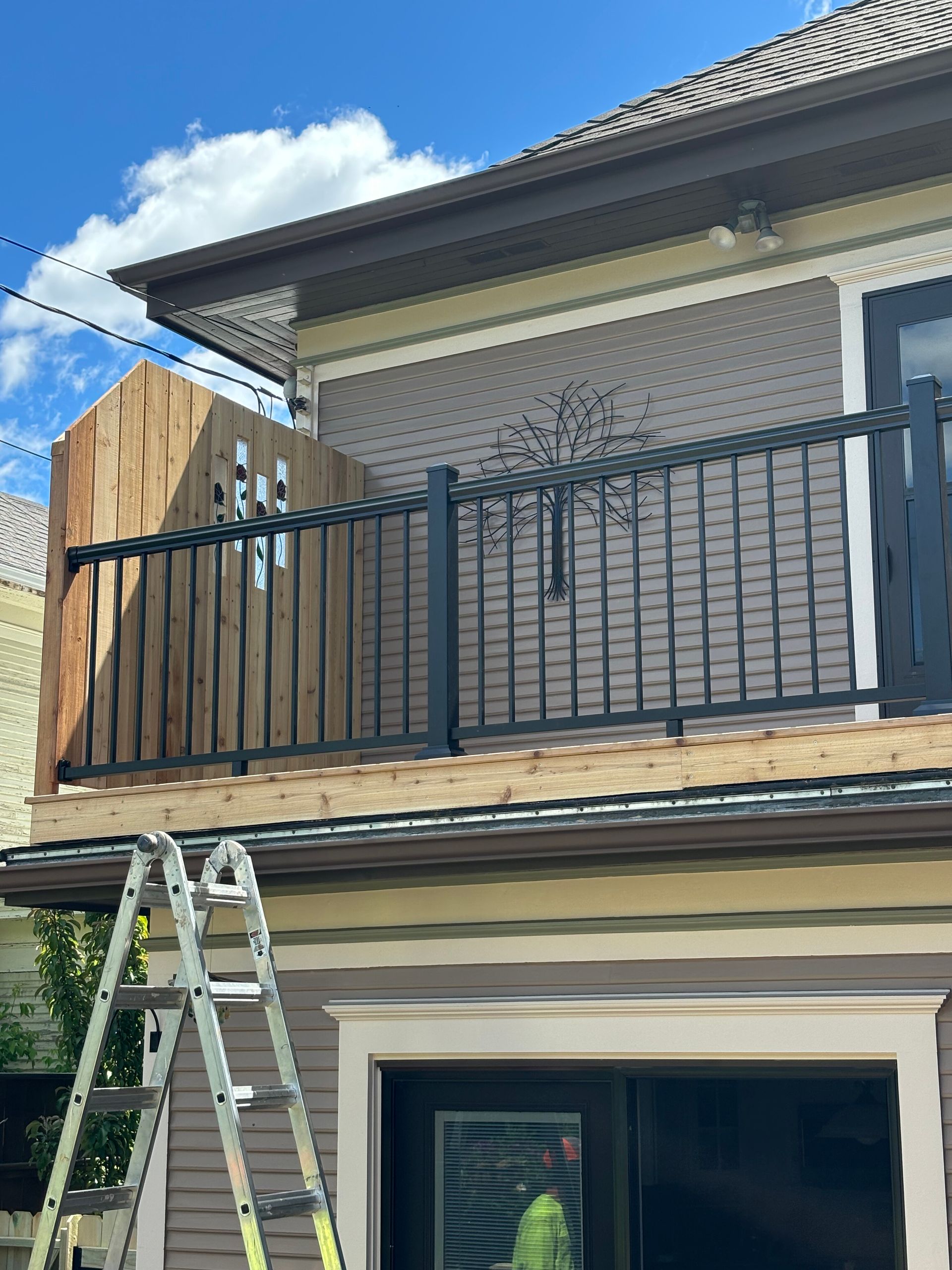 Construction of a deck railing on a house, with a ladder visible.
