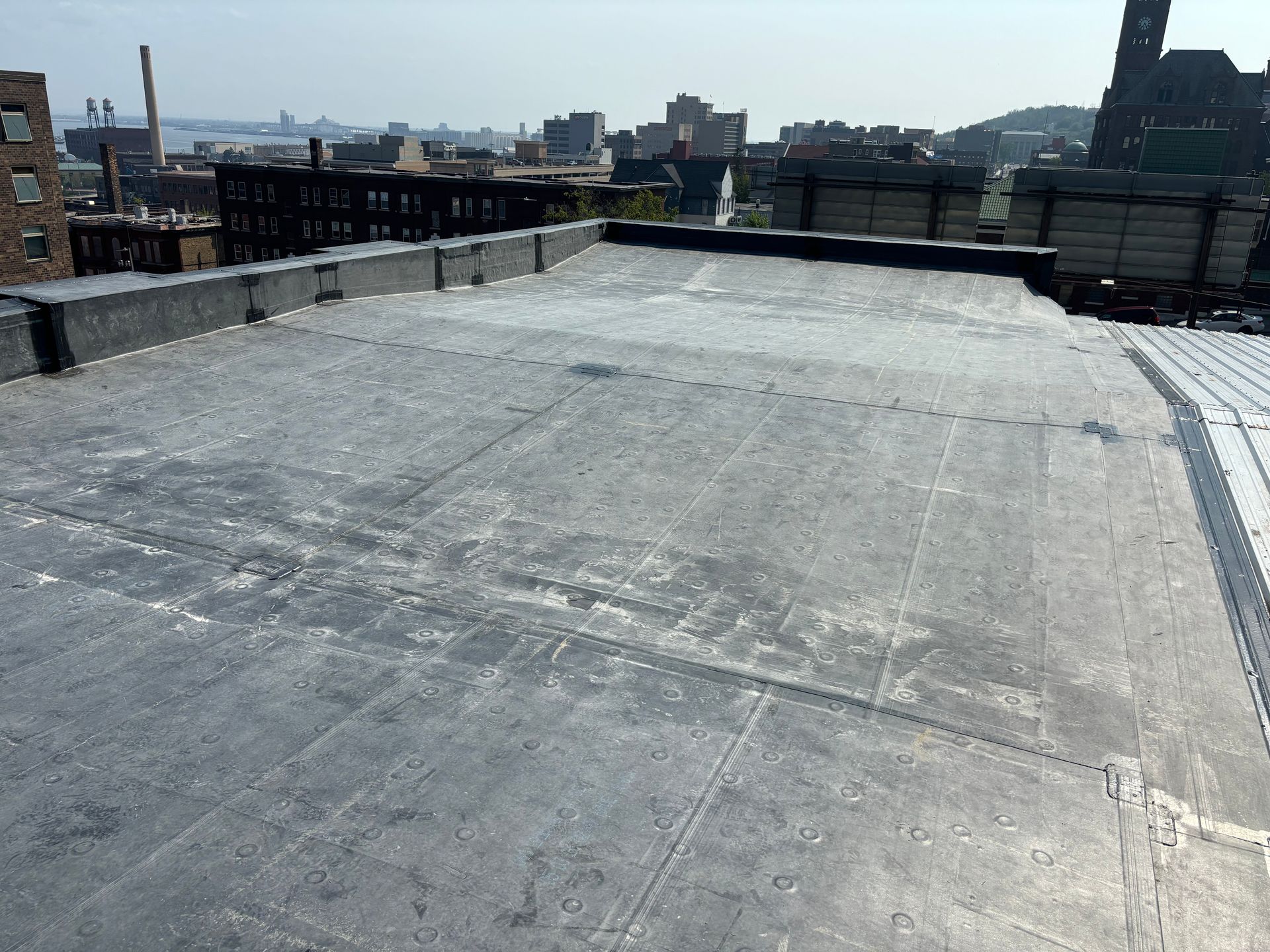 A flat, gray rooftop with a city skyline in the background.
