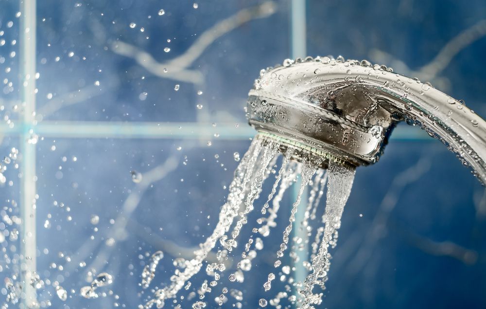 Shower Head Spraying Water. Blue Tile Background — Illawater Hot Water Services in Sutherland Shire, NSW