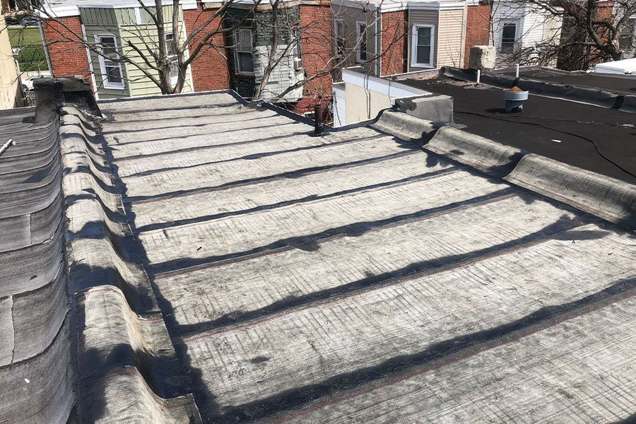 A roof with a lot of shingles on it and a brick building in the background.