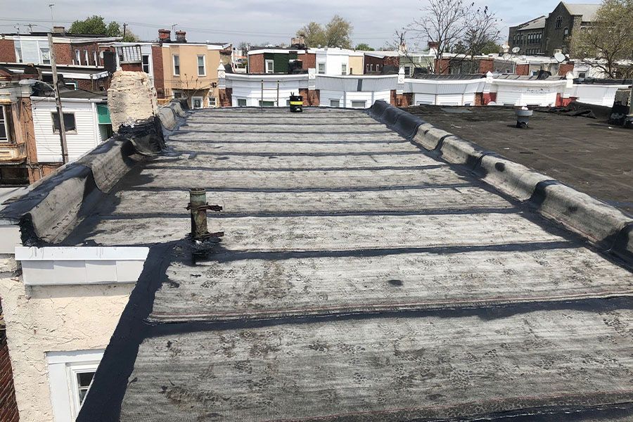 A roof with a lot of shadows on it and a lot of buildings in the background.