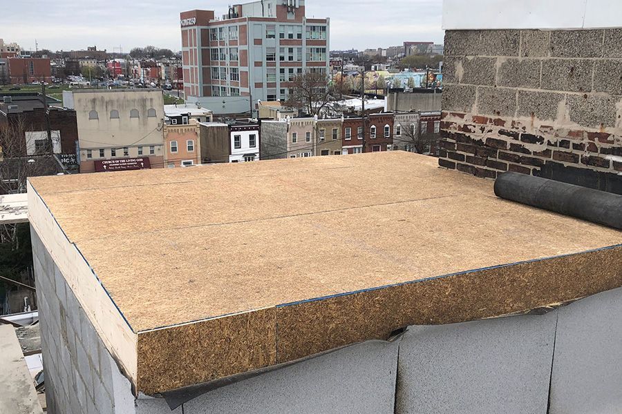 A large piece of wood is sitting on top of a brick wall.