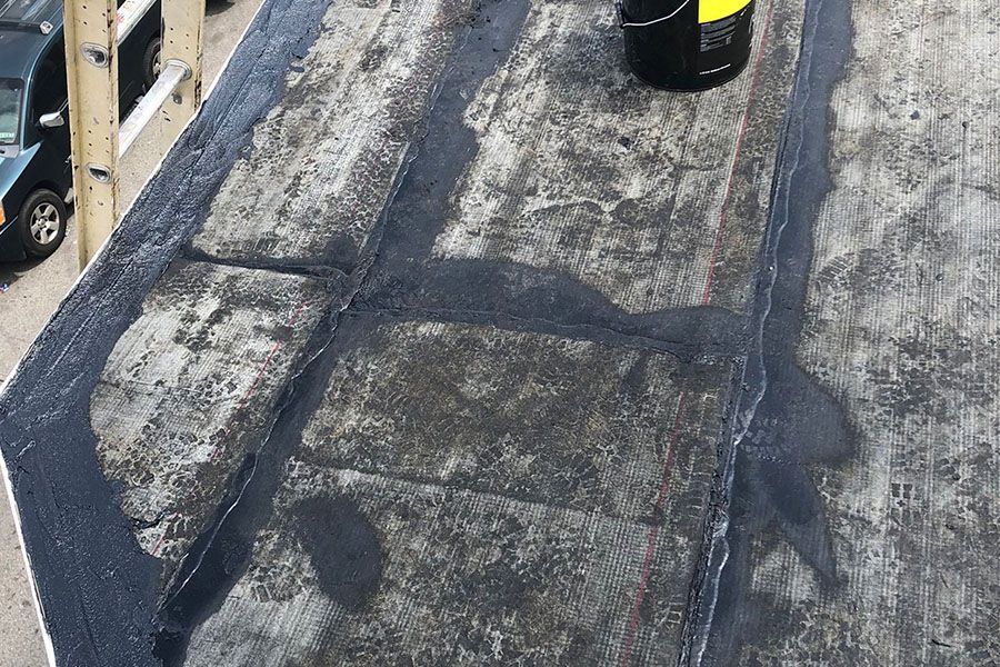 A bucket of liquid is sitting on top of a concrete roof.