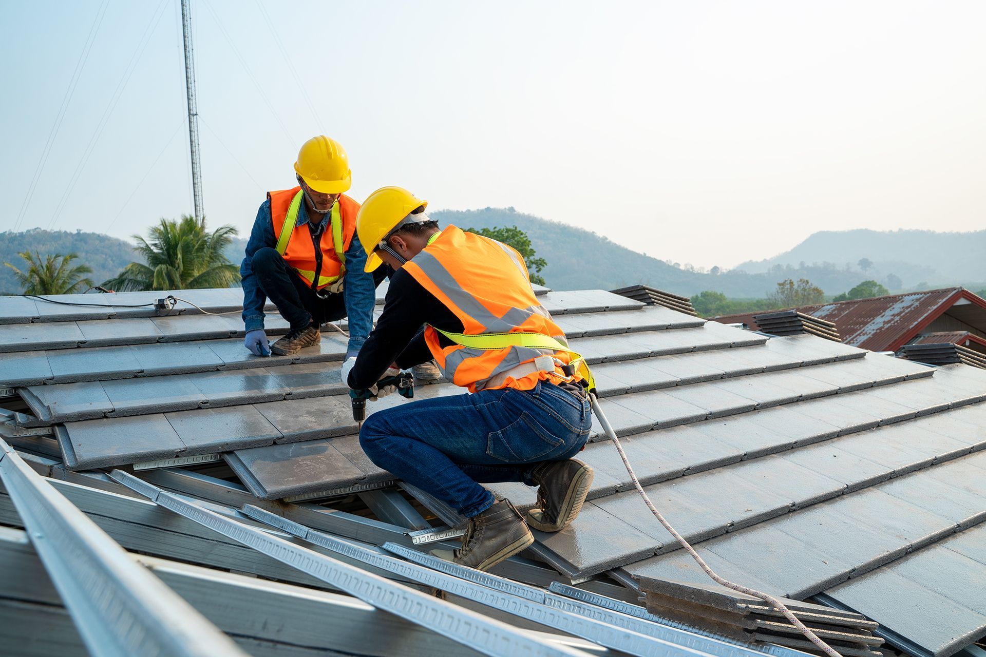 Two construction workers are installing solar panels on the roof of a building.