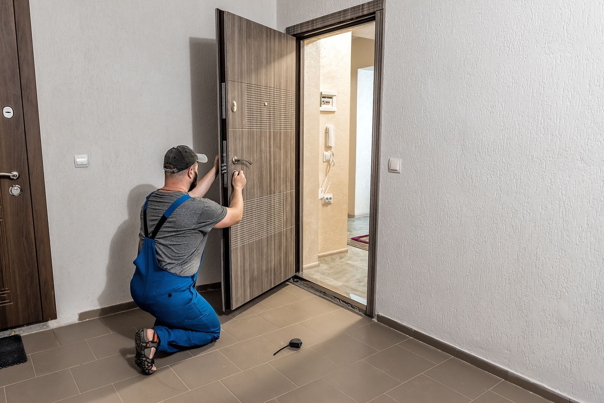 A man is kneeling down to fix a door in a room.