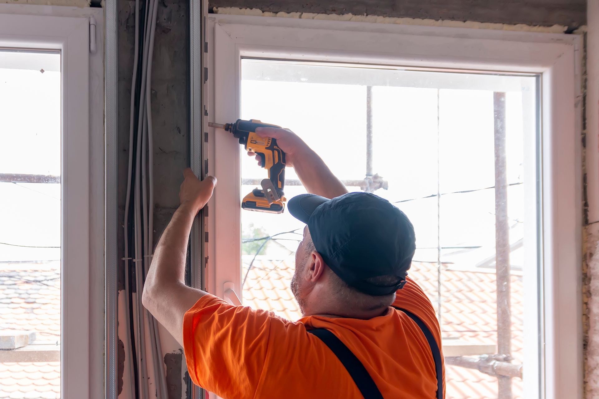 A man is installing a window with a drill.