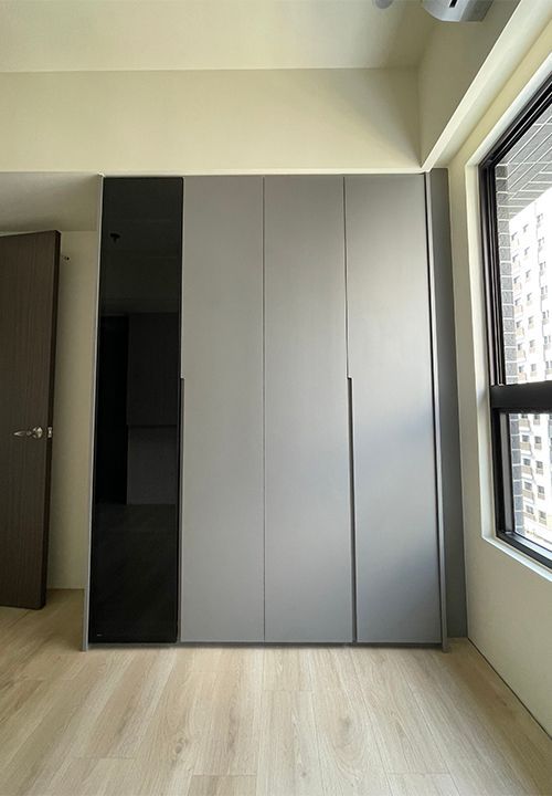 A bedroom with a large wardrobe and a window.