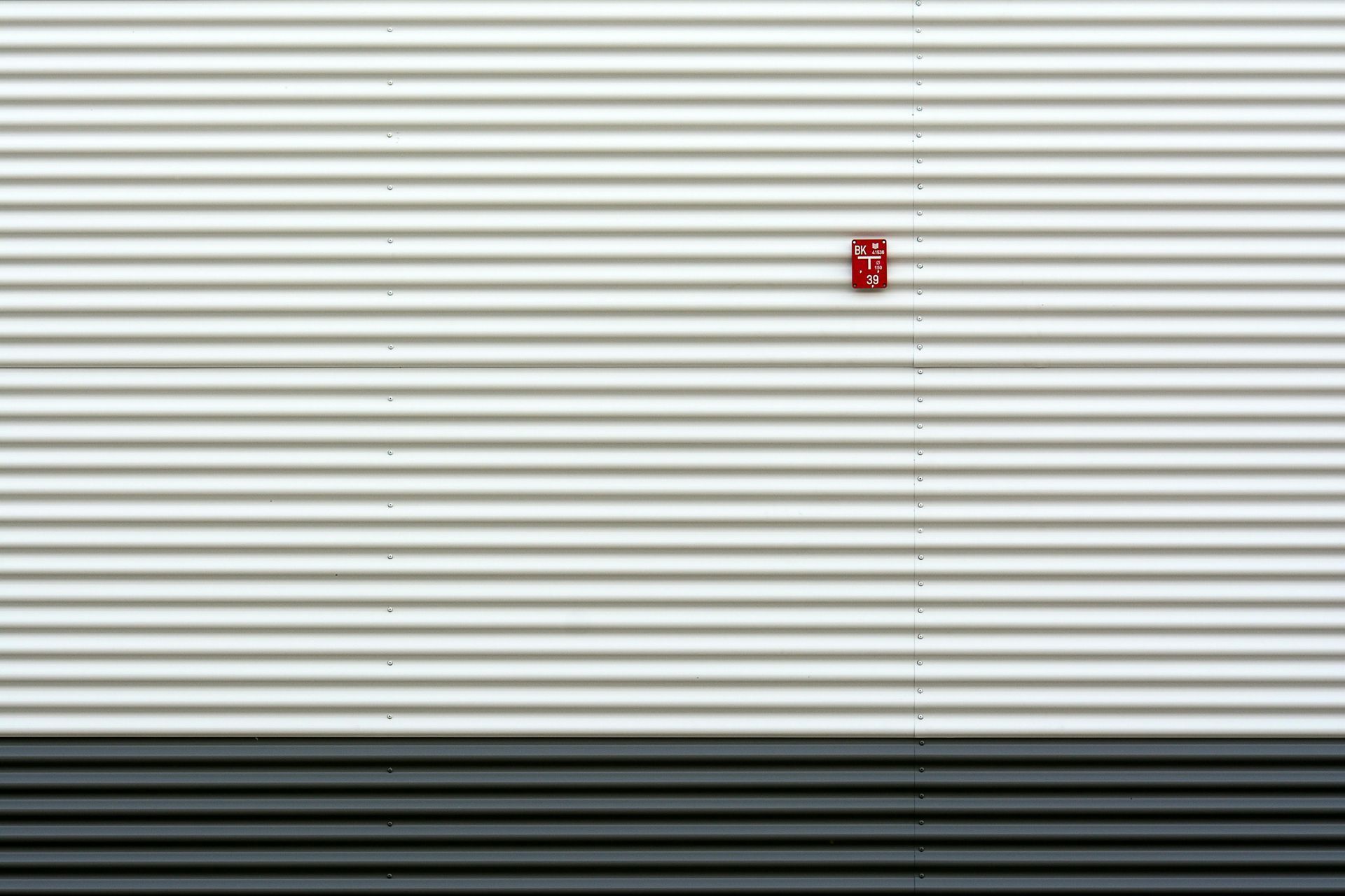 A white and black wall with a red fire alarm on it.