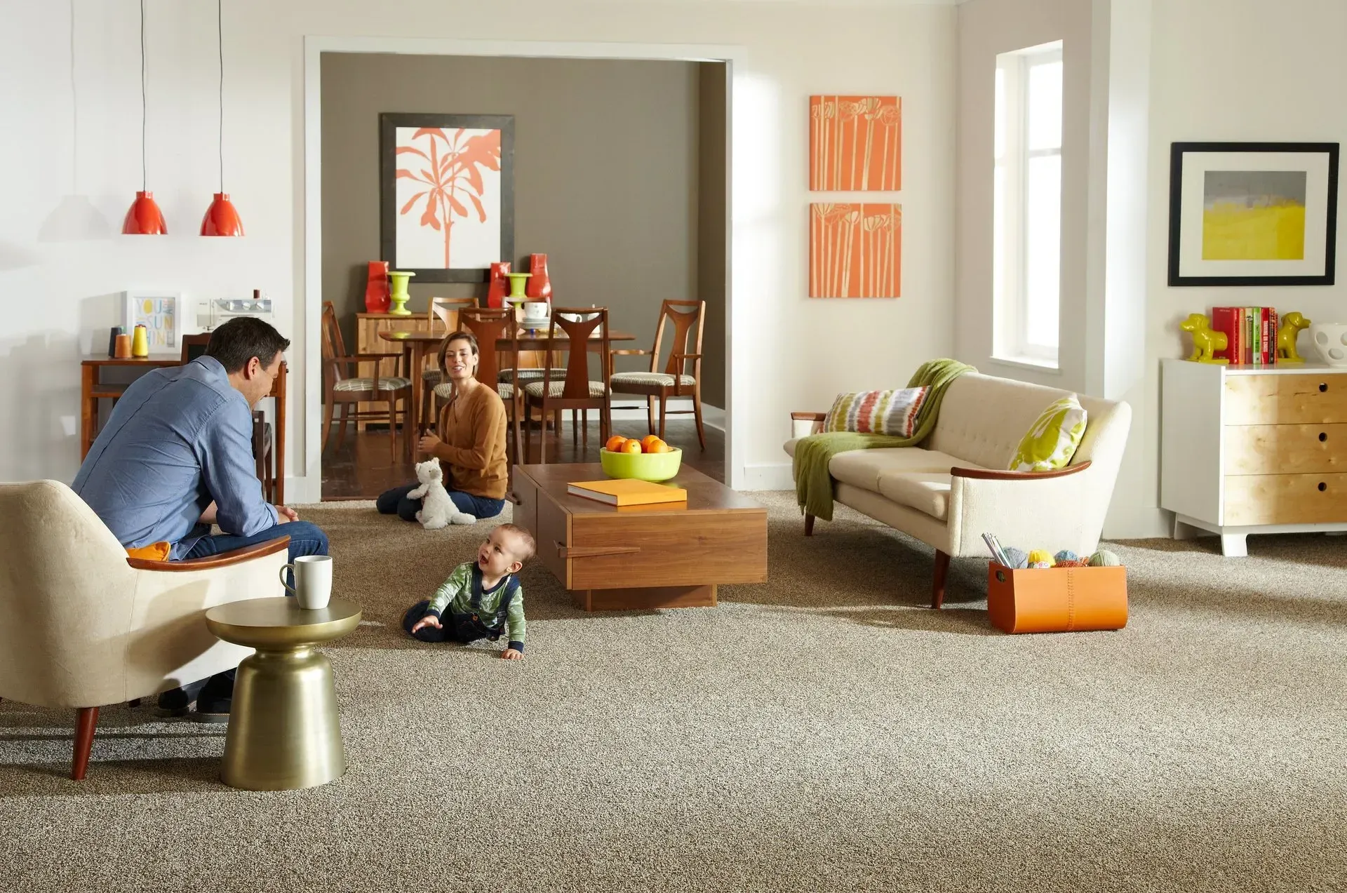 A man is sitting on a couch in a living room with two children playing on the floor