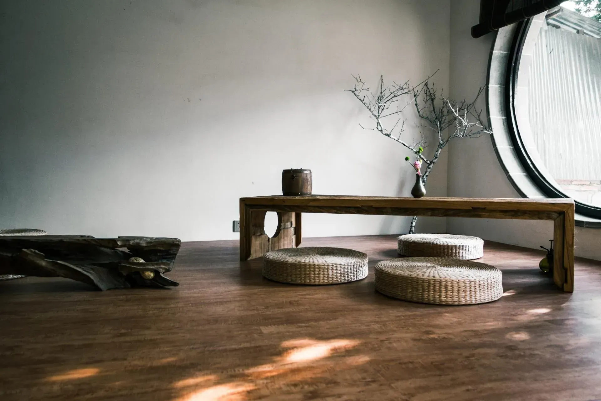 A room with a wooden table and wicker cushions on the floor