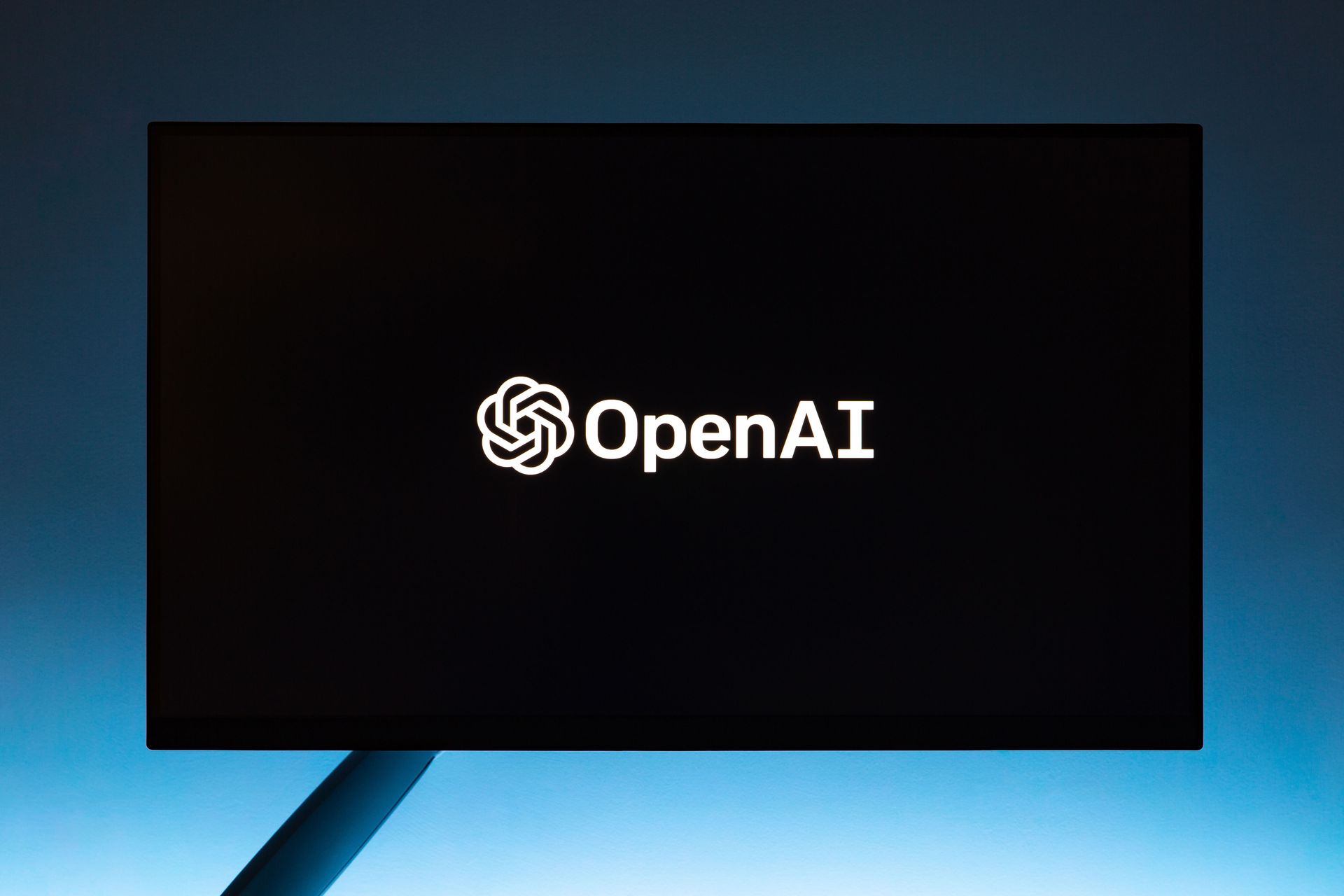 OpenAI logo on a black screen against a blue background