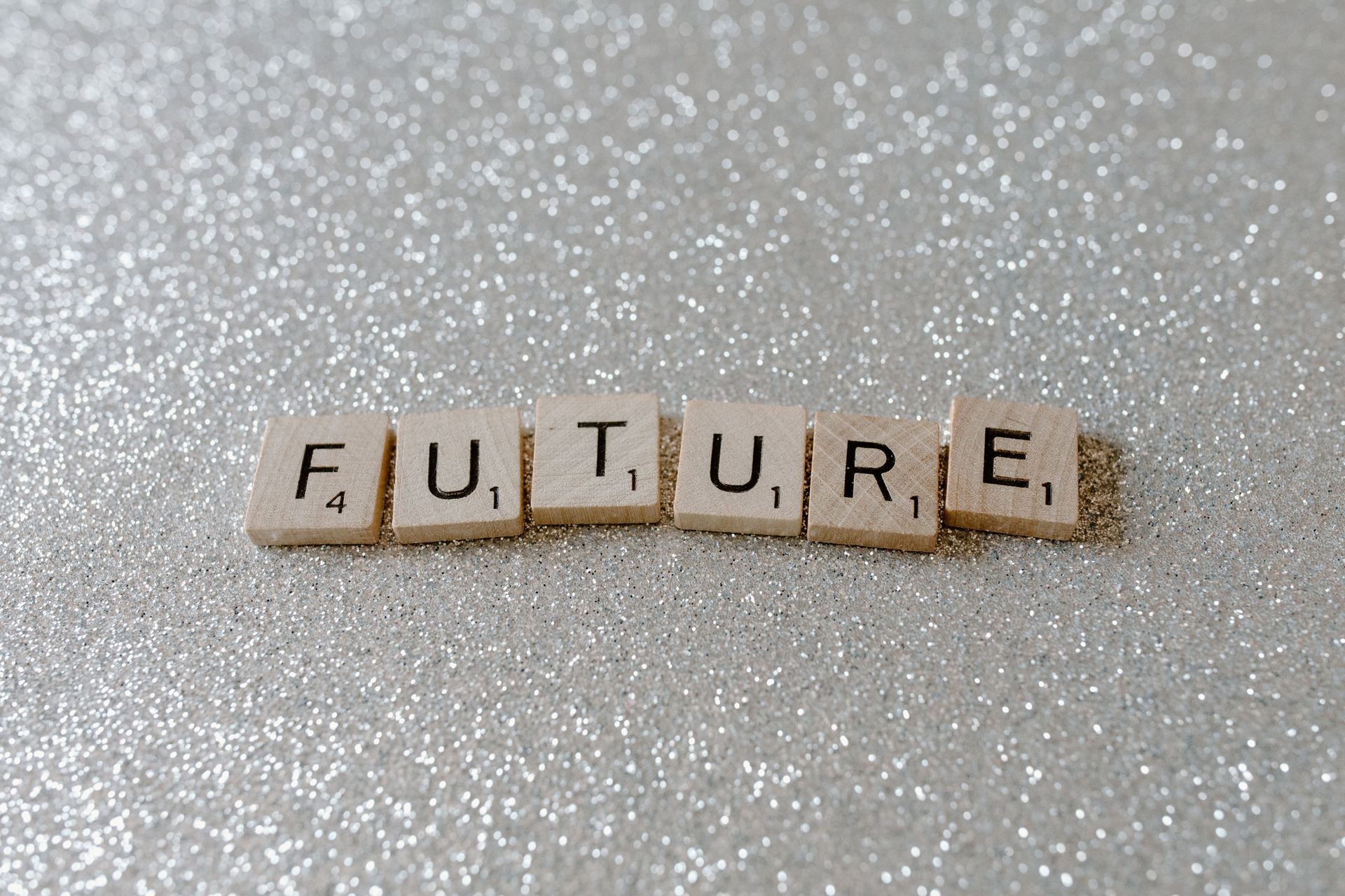 Scrabble tiles spelling “FUTURE” on a sparkly gray surface