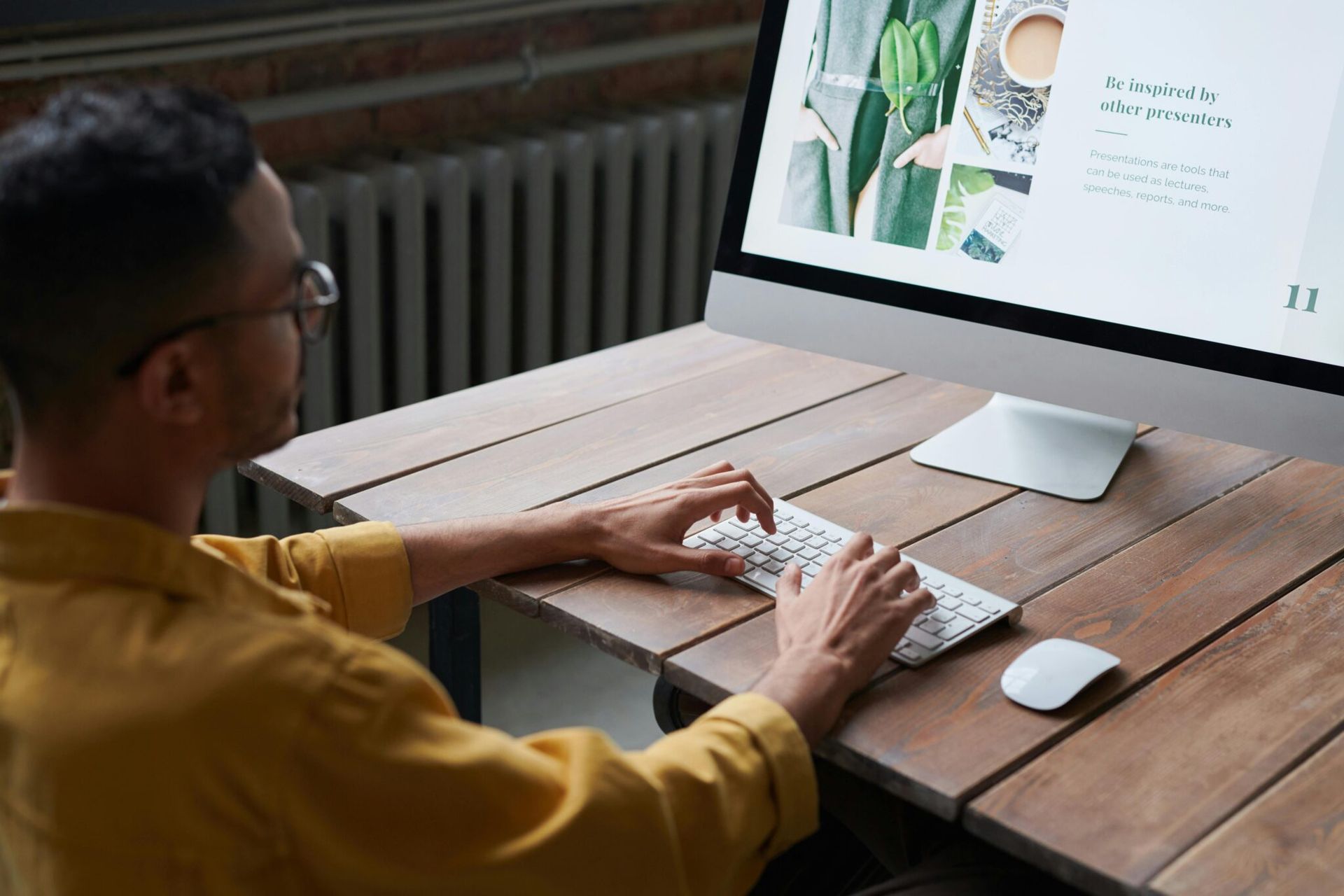 Person typing at a desktop computer on a wooden desk, viewing a web page with a plant image.