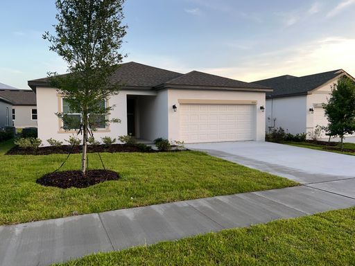 White suburban house with a gray roof and a green lawn.