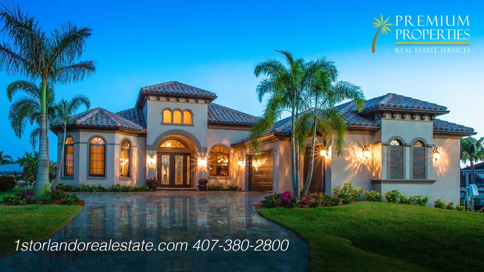 Luxurious beige home with palm trees, glowing lights, and curved driveway.
