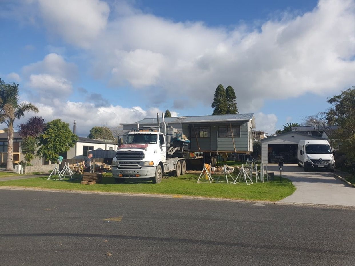 Suburban street with a white truck, house, driveway, and lawn under a partly cloudy sky