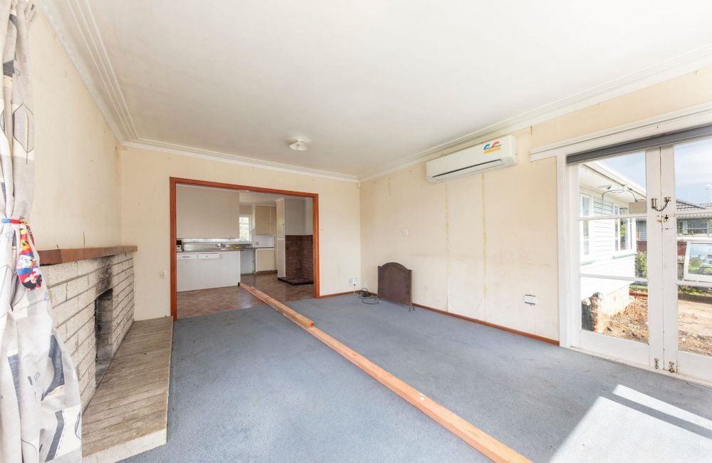 Empty living room with blue carpet, fireplace, air conditioner, and sliding glass door to a patio.