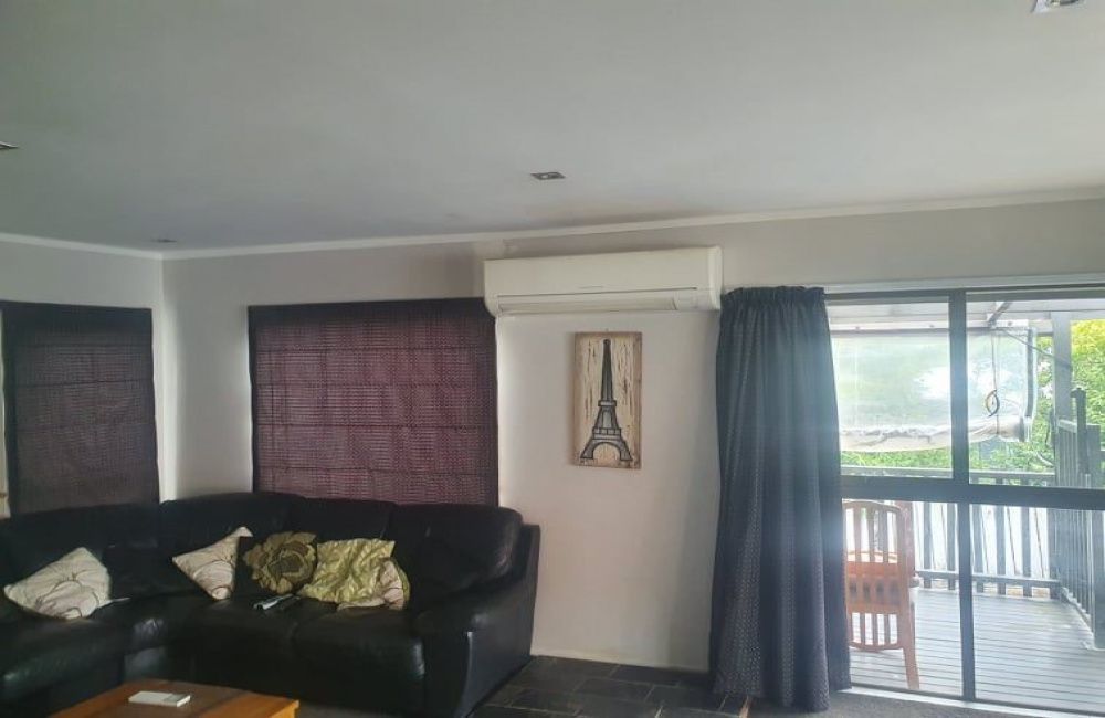 Living room with black sofa, dark window blinds, wall art, and a sliding door to a balcony.