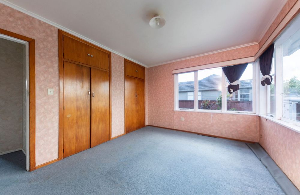 Empty bedroom with blue carpet, wood closet doors, and large windows on pink walls
