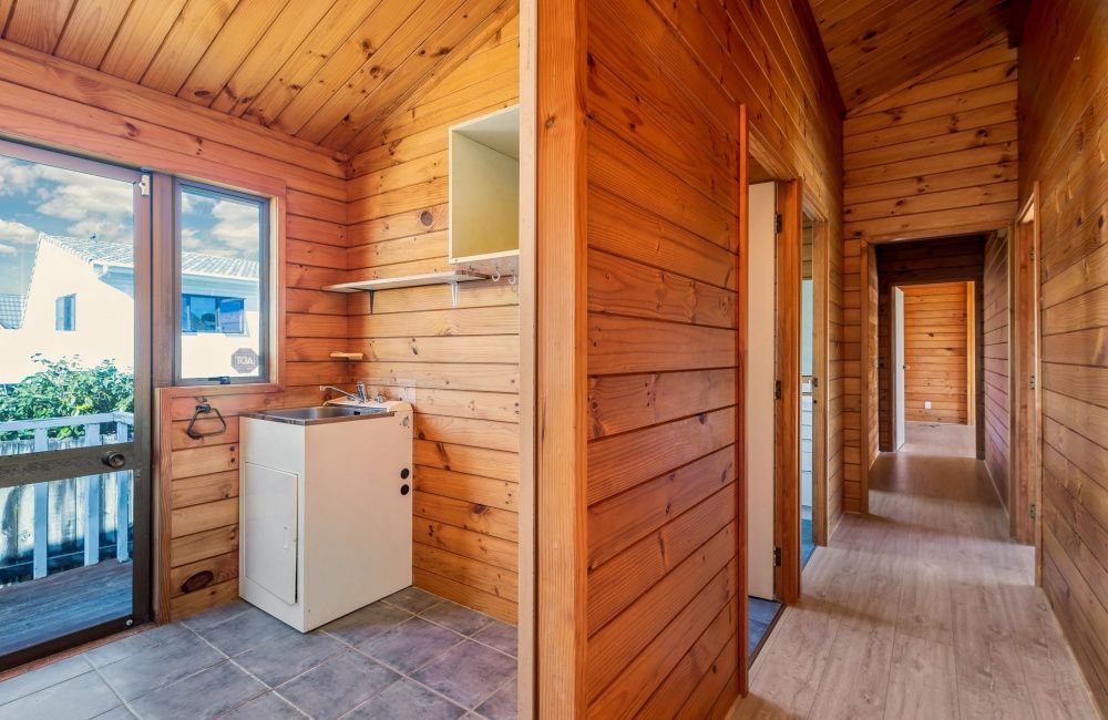 Wood-paneled hallway and small kitchen nook with a window, sink, and tile floor in a cozy cabin interior