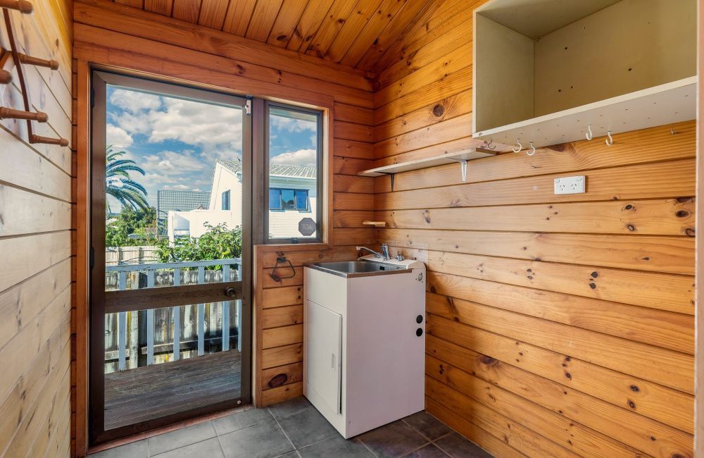 Small wood-paneled balcony room with a white cabinet and a view through the door to the outdoors