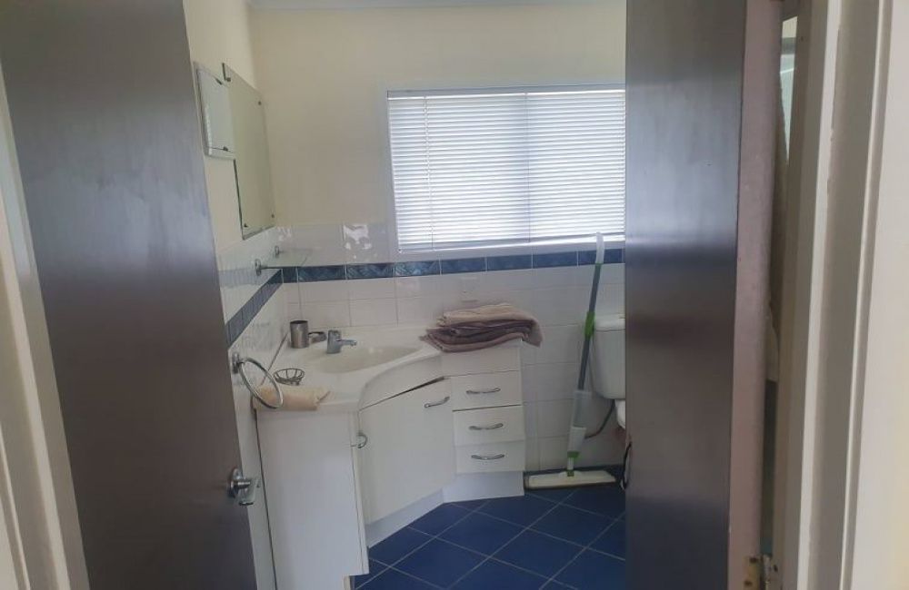 Small kitchen with white cabinets, blue tile floor, and a window with blinds.