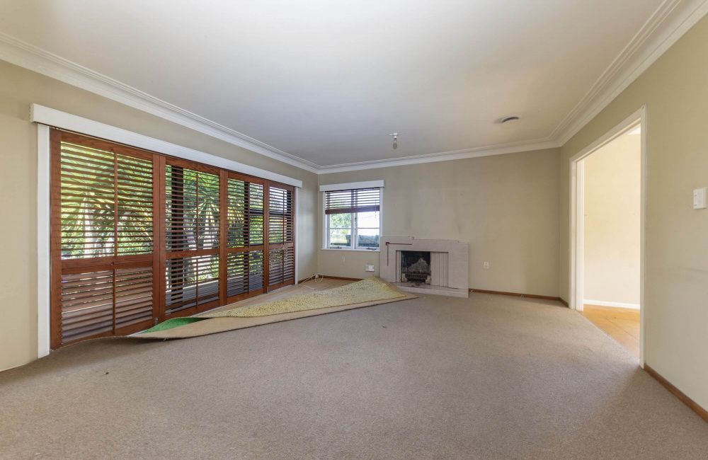 Empty beige living room with carpet, fireplace, and sliding doors to a covered patio